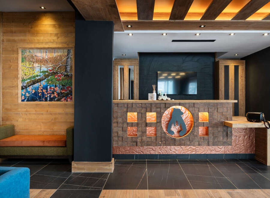 This hotel boasts a stunning reception area with a unique copper and wood design, featuring a backlit bear logo.