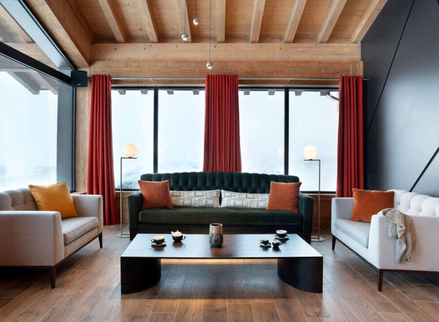 Luxurious chalet living room with floor-to-ceiling windows offering breathtaking mountain views.