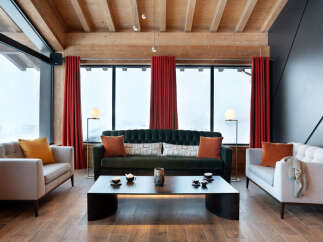 Luxurious chalet living room with floor-to-ceiling windows offering breathtaking mountain views.