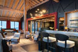 This stunning hotel lobby boasts a modern design with exposed wooden beams, a cozy seating area, and a sleek bar.