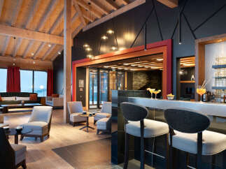 This stunning hotel lobby boasts a modern design with exposed wooden beams, a cozy seating area, and a sleek bar.