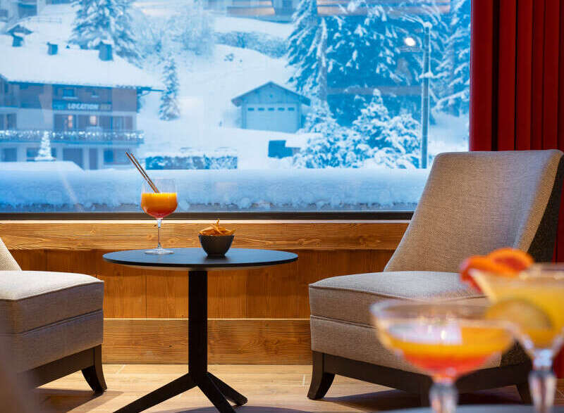 Cozy lounge area with stunning views of a snow-covered mountain village.