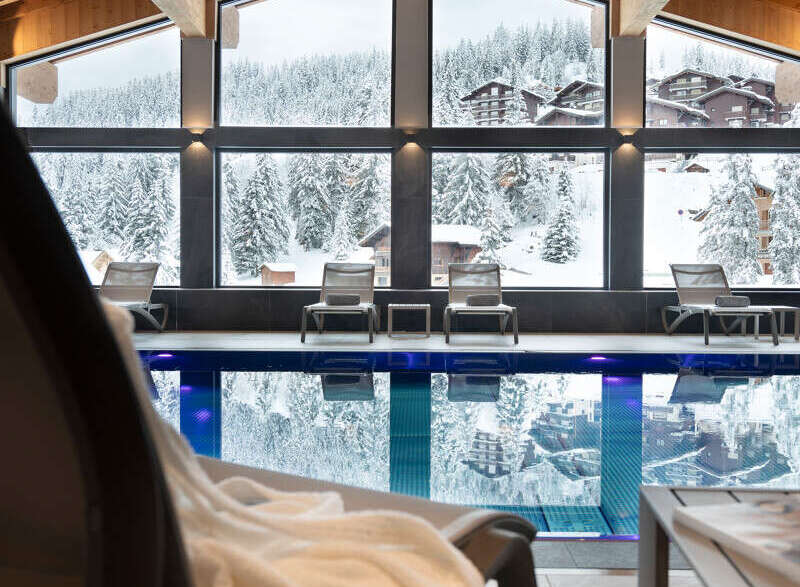 Indulge in the ultimate relaxation experience at our luxurious hotel, featuring a stunning indoor pool with floor-to-ceiling windows offering breathtaking views of the snow-capped mountains.