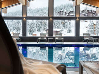 Indulge in the ultimate relaxation experience at our luxurious hotel, featuring a stunning indoor pool with floor-to-ceiling windows offering breathtaking views of the snow-capped mountains.