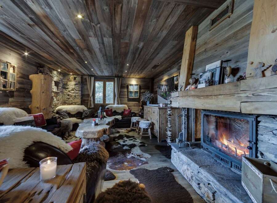 Cozy up by the fireplace in this rustic-chic chalet, featuring a wood-paneled ceiling and stone accents.