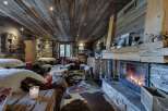 Cozy up by the fireplace in this rustic-chic chalet, featuring a wood-paneled ceiling and stone accents.