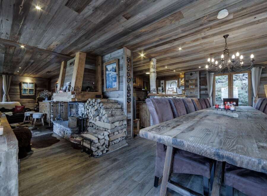 This stunning chalet boasts a spacious open-plan living area with a rustic wooden dining table perfect for large gatherings.