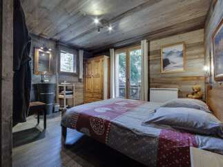 Cozy chalet bedroom with rustic wood walls and floors, featuring a comfortable double bed and a private bathroom.