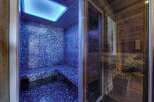 Indulge in ultimate relaxation in this stunning private steam room, featuring a sleek blue mosaic design and a calming blue light.