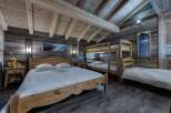 Rustic mountain chalet bedroom with wooden bunk beds and a large wooden bed.