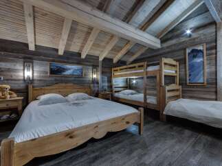 Rustic mountain chalet bedroom with wooden bunk beds and a large wooden bed.
