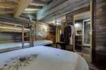 Cozy chalet bedroom with rustic wood walls and a bunk bed, perfect for families.