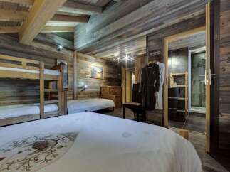 Cozy chalet bedroom with rustic wood walls and a bunk bed, perfect for families.