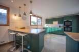 This stunning kitchen boasts a modern design with sleek green cabinetry and a spacious layout.