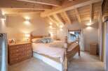 Discover the charm of this cozy bedroom, featuring a rustic wooden bed and a warm, inviting ambiance.