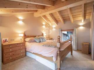 Discover the charm of this cozy bedroom, featuring a rustic wooden bed and a warm, inviting ambiance.