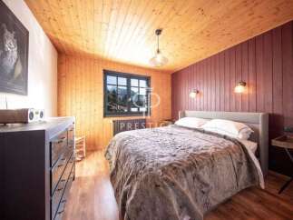 This cozy bedroom features a warm wooden ceiling and walls, creating a rustic and inviting atmosphere.