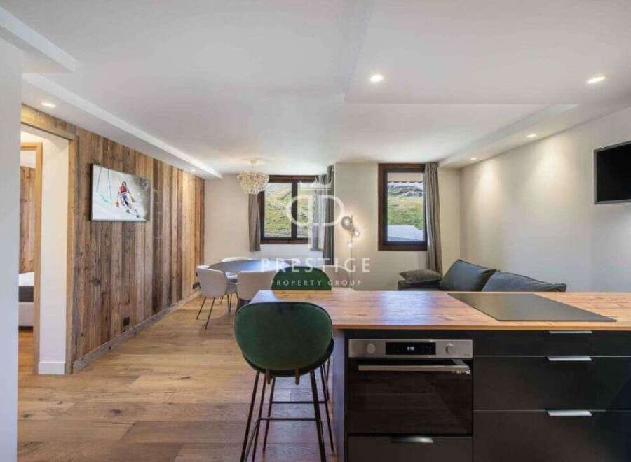 Experience luxury living in this stunning property, featuring a modern kitchen with sleek black cabinetry and a cozy seating area.