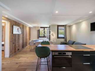 Experience luxury living in this stunning property, featuring a modern kitchen with sleek black cabinetry and a cozy seating area.
