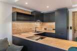 Modern kitchen design with sleek black cabinetry and a warm wooden countertop.