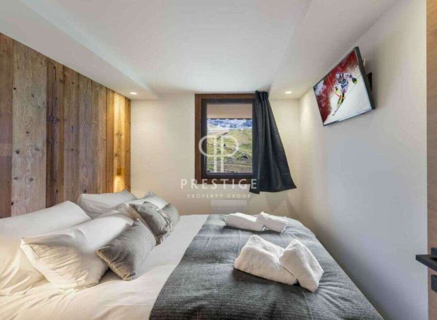 Experience luxury in this stunning property, featuring a cozy bedroom with a wooden accent wall.