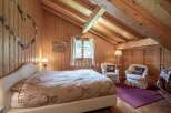 Cozy bedroom with wooden walls and ceiling, creating a warm and inviting atmosphere.