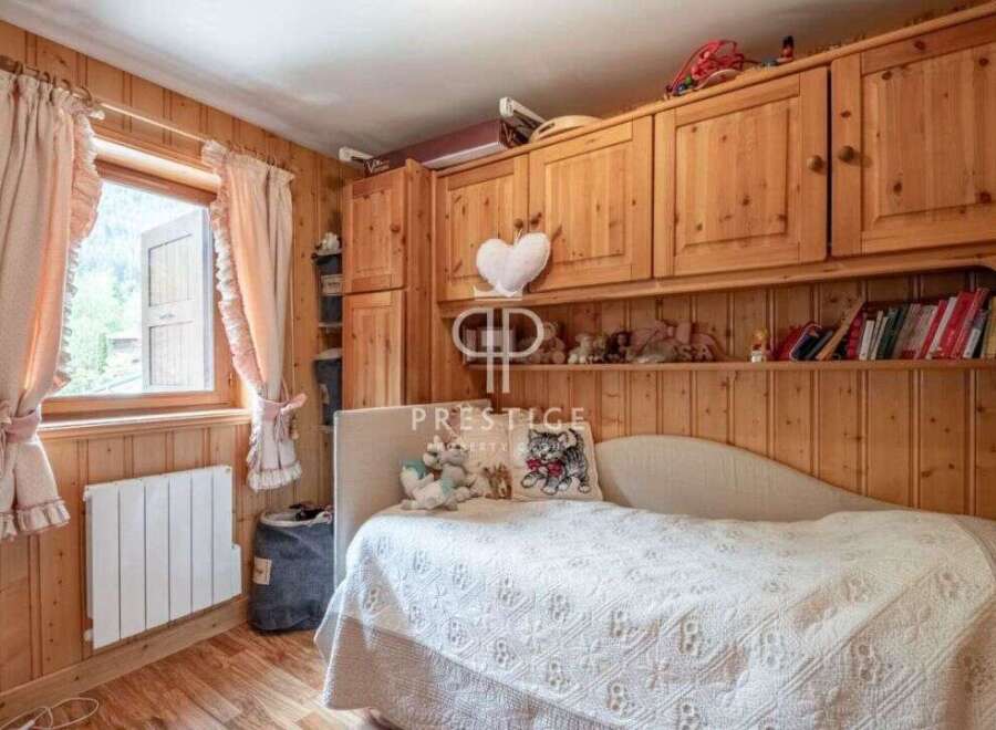Cozy bedroom with wooden paneling and a charming window view.