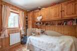 Cozy bedroom with wooden paneling and a charming window view.