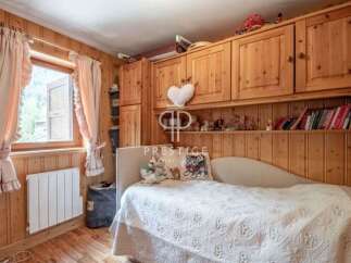 Cozy bedroom with wooden paneling and a charming window view.