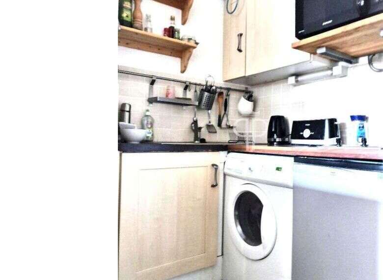 Cozy kitchen with a washing machine and a microwave.