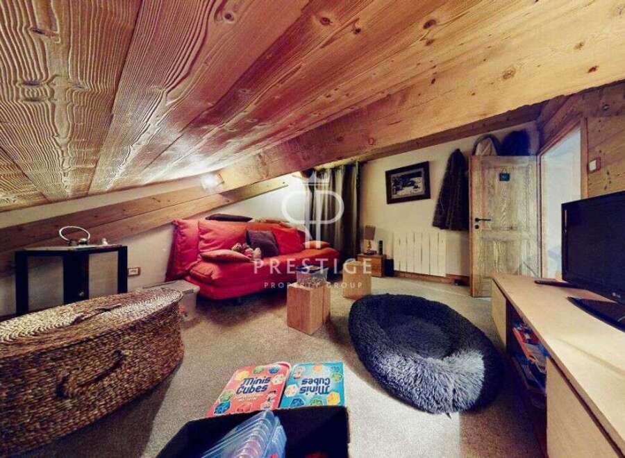 Discover the charm of this unique property, featuring a cozy living space with a distinctive sloped ceiling and exposed wooden beams.