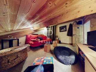 Discover the charm of this unique property, featuring a cozy living space with a distinctive sloped ceiling and exposed wooden beams.