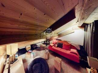 Discover the charm of this unique property, featuring a cozy living space with a distinctive sloped ceiling and exposed wooden beams.