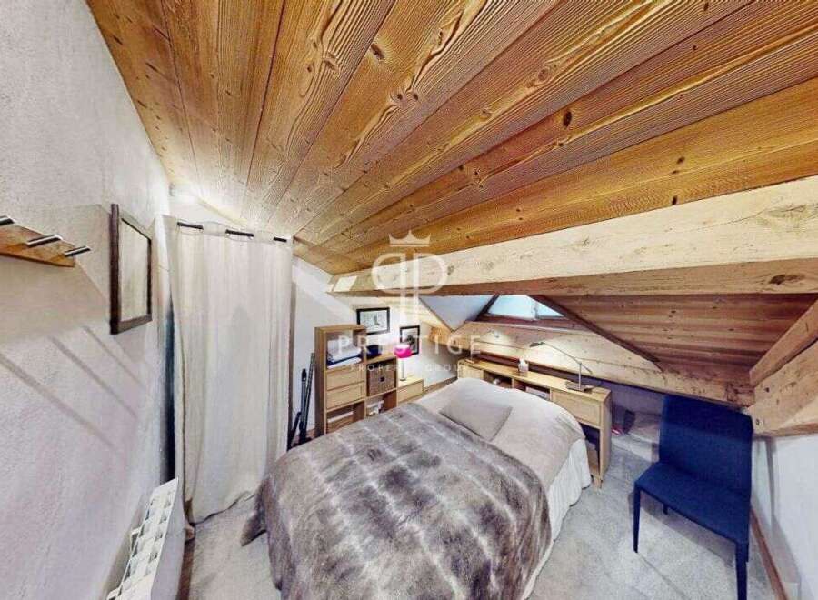 Discover the charm of this cozy bedroom with its unique wooden ceiling and exposed beams.
