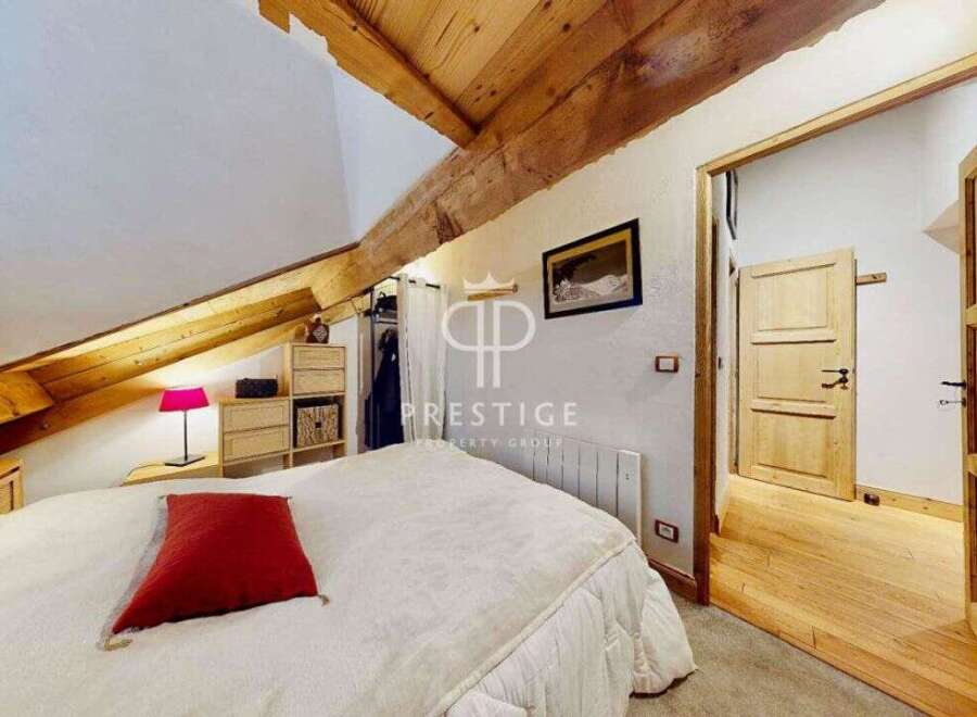 Discover the charm of this cozy bedroom, featuring a unique sloped ceiling with exposed wooden beams.