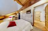 Discover the charm of this cozy bedroom, featuring a unique sloped ceiling with exposed wooden beams.