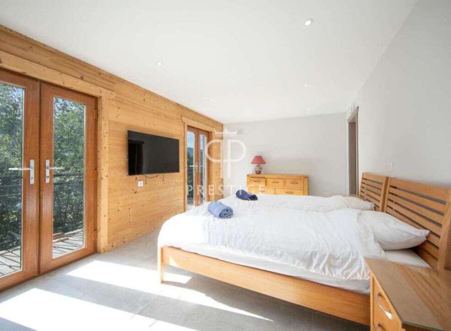 Discover a cozy bedroom with a wooden bed frame and a stylish TV.