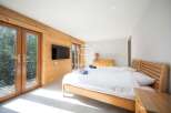 Discover a cozy bedroom with a wooden bed frame and a stylish TV.