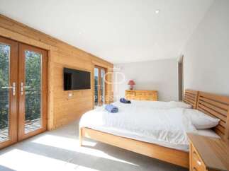 Discover a cozy bedroom with a wooden bed frame and a stylish TV.