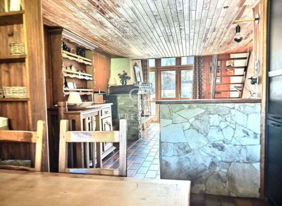 Discover the charm of this rustic property, featuring a cozy interior with wooden accents and a unique stone wall.