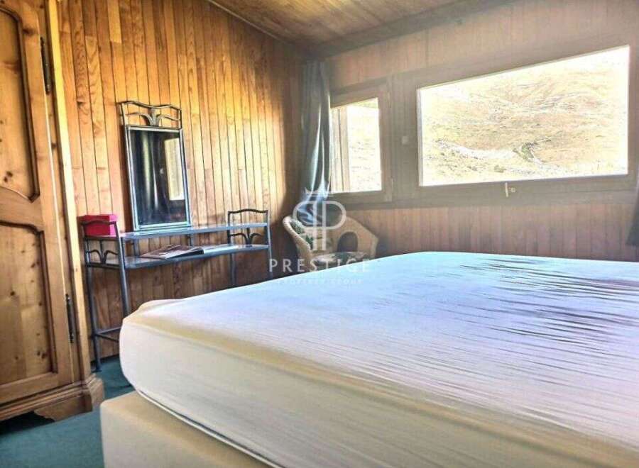 Cozy bedroom with wooden paneling and a large window offering scenic views.