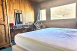 Cozy bedroom with wooden paneling and a large window offering scenic views.
