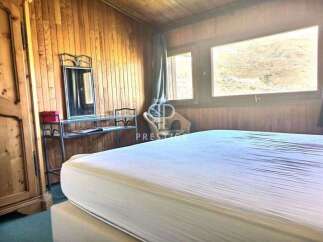 Cozy bedroom with wooden paneling and a large window offering scenic views.