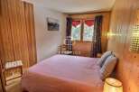 Cozy bedroom with wooden paneling and a comfortable bed.