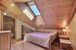 Discover the charm of this cozy bedroom with its unique wooden ceiling and walls.