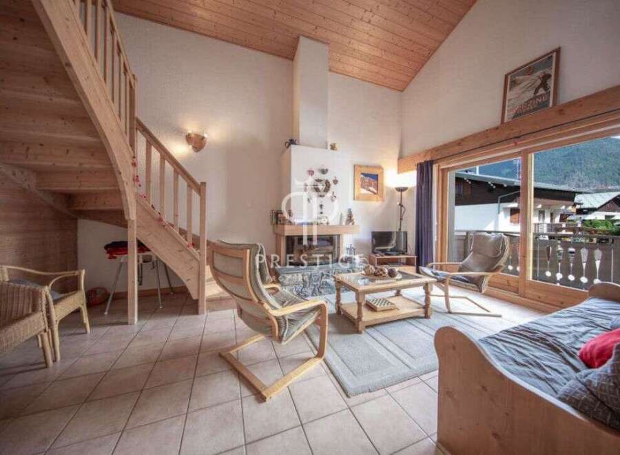 Discover a cozy chalet with a stunning wooden staircase and a warm fireplace, perfect for a relaxing getaway.