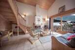 Discover a cozy chalet with a stunning wooden staircase and a warm fireplace, perfect for a relaxing getaway.