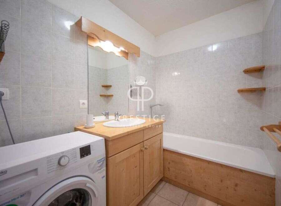 Discover a charming bathroom with a rustic wooden vanity and a convenient washing machine.