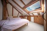 Discover the charm of this unique bedroom with exposed wooden beams and a skylight that floods the space with natural light.