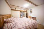 Discover the charm of this cozy bedroom, featuring exposed wooden beams and a rustic aesthetic.